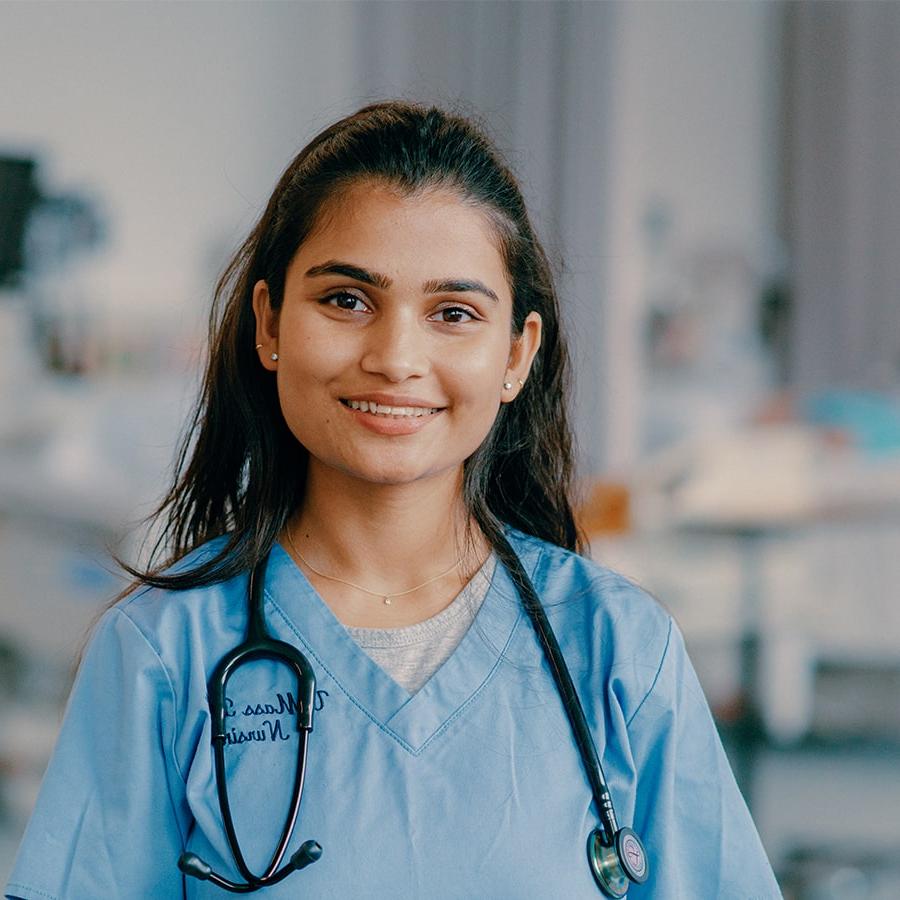 Anjali in nursing scrubs stands in nursing lab.